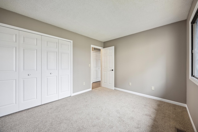 unfurnished bedroom with light carpet, a closet, and a textured ceiling