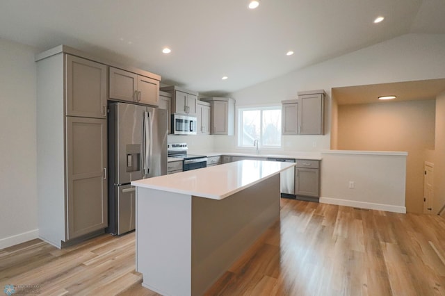 kitchen with a center island, light wood-type flooring, lofted ceiling, and appliances with stainless steel finishes