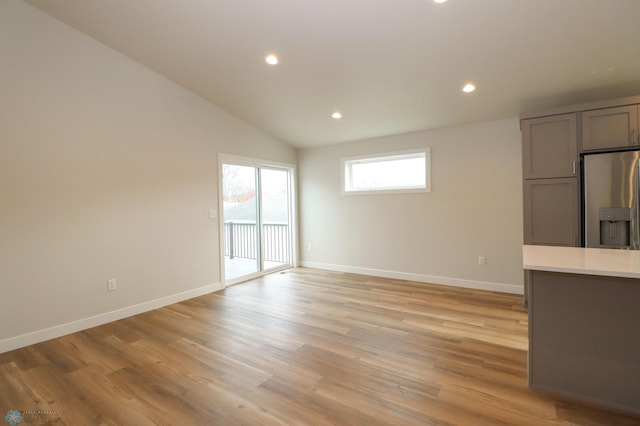 unfurnished living room featuring vaulted ceiling and light wood-type flooring