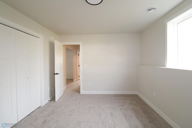 unfurnished bedroom with light carpet and a closet