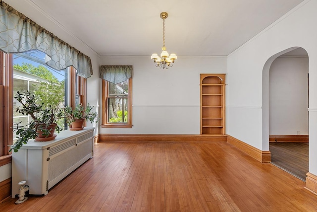 spare room featuring hardwood / wood-style floors, crown molding, and an inviting chandelier