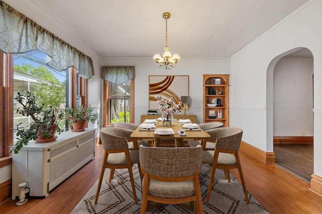 dining space featuring an inviting chandelier, ornamental molding, and light hardwood / wood-style flooring