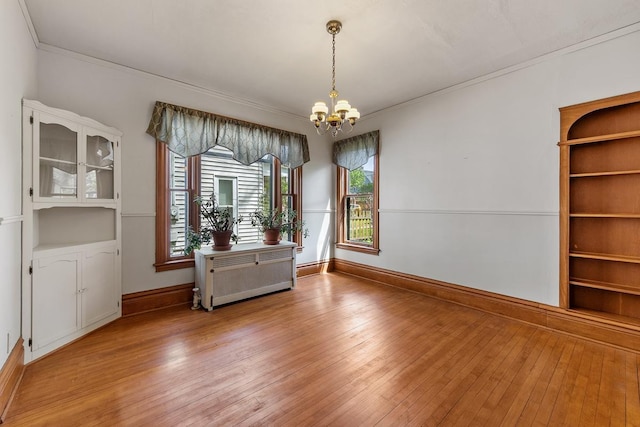 unfurnished dining area with a chandelier, hardwood / wood-style floors, and crown molding