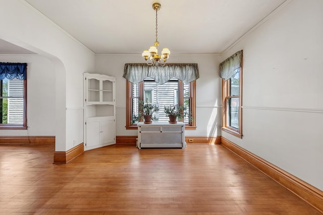 unfurnished dining area with light wood-type flooring, crown molding, and a chandelier