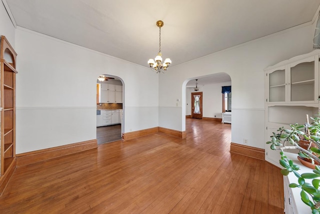 unfurnished room with wood-type flooring, ceiling fan with notable chandelier, and ornamental molding