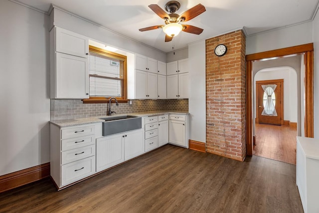 kitchen featuring dark wood-type flooring, sink, decorative backsplash, ceiling fan, and white cabinetry