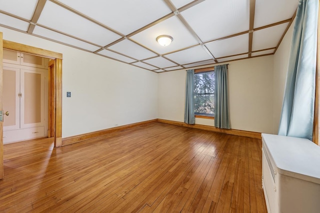 spare room featuring light wood-type flooring and coffered ceiling