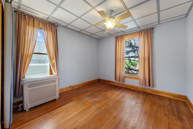 unfurnished room with ceiling fan, light hardwood / wood-style floors, and radiator heating unit