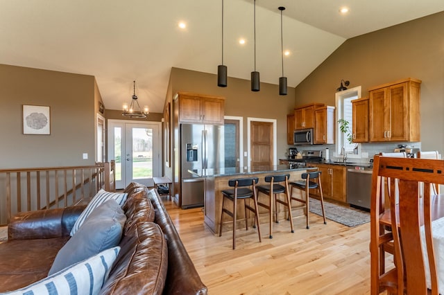 kitchen with a kitchen breakfast bar, tasteful backsplash, decorative light fixtures, a kitchen island, and stainless steel appliances