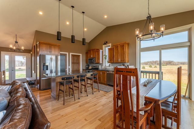 dining area featuring a notable chandelier, vaulted ceiling, sink, and light hardwood / wood-style flooring