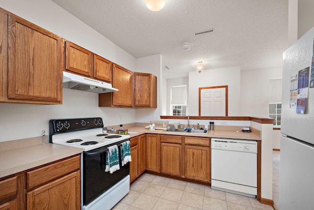 kitchen with a textured ceiling, kitchen peninsula, white appliances, and sink