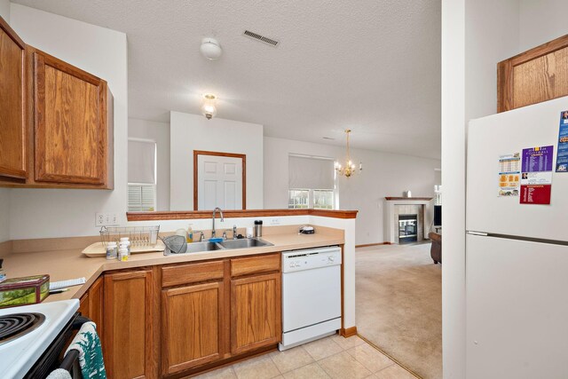 kitchen with white appliances, a tile fireplace, sink, a textured ceiling, and a notable chandelier