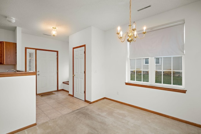 unfurnished dining area featuring light carpet, a textured ceiling, and an inviting chandelier