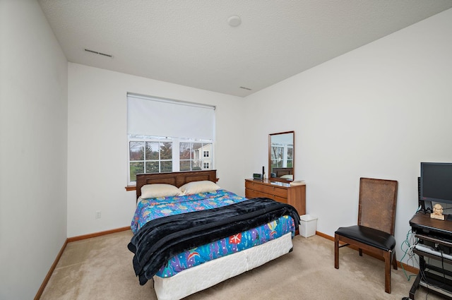 bedroom with light colored carpet and a textured ceiling