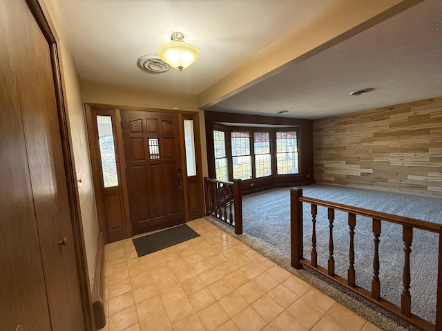 foyer featuring wood walls and a textured ceiling