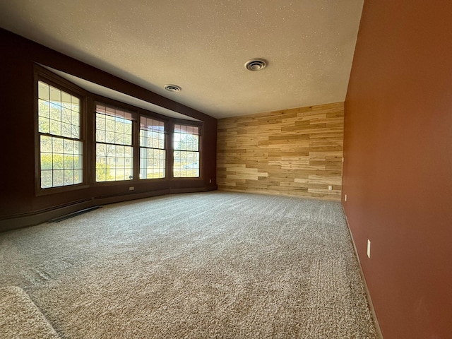 empty room featuring carpet, lofted ceiling, a textured ceiling, and wooden walls