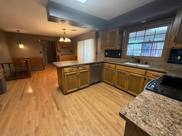 kitchen featuring decorative light fixtures, dishwasher, kitchen peninsula, and sink