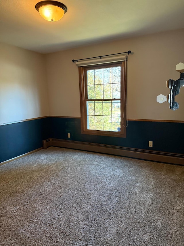 carpeted empty room with a baseboard heating unit