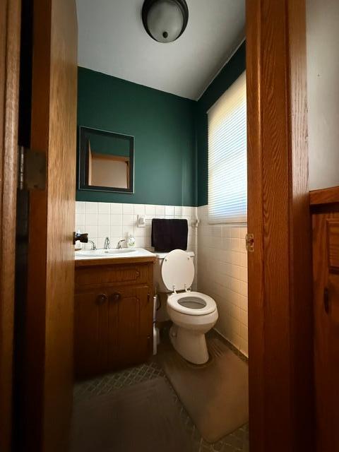 bathroom featuring vanity, toilet, and tile walls