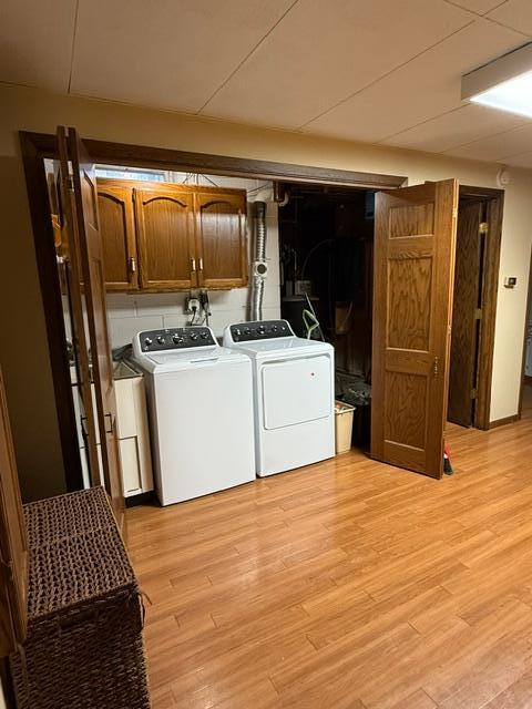 laundry area featuring washer and dryer, cabinets, and light wood-type flooring