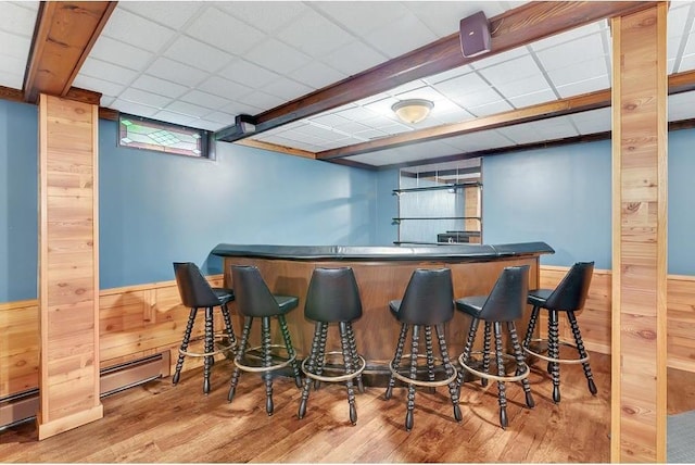 bar with wooden walls, a baseboard heating unit, and hardwood / wood-style flooring