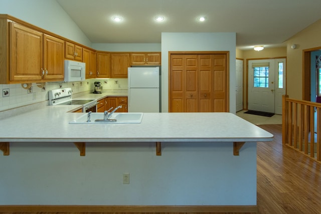 kitchen with kitchen peninsula, a kitchen breakfast bar, white appliances, and sink