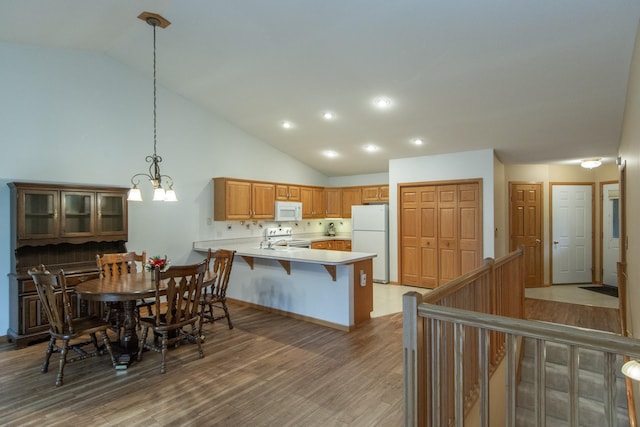 dining room with hardwood / wood-style floors, high vaulted ceiling, and a notable chandelier