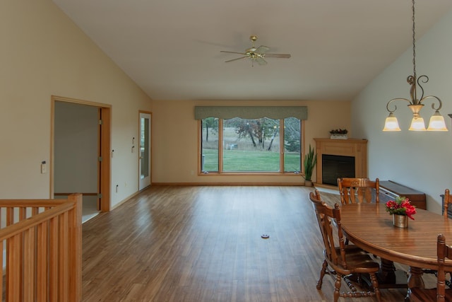 dining area with ceiling fan with notable chandelier, wood-type flooring, and high vaulted ceiling