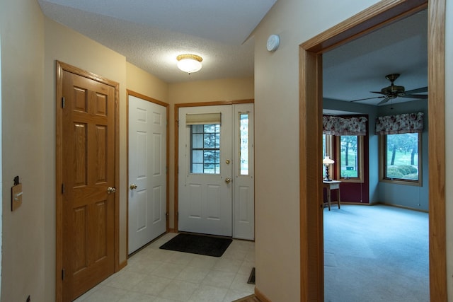 foyer entrance featuring light carpet, a textured ceiling, and ceiling fan