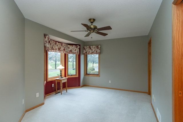 unfurnished room with ceiling fan, light carpet, and a textured ceiling