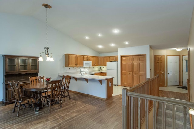 dining room featuring hardwood / wood-style floors, high vaulted ceiling, and an inviting chandelier