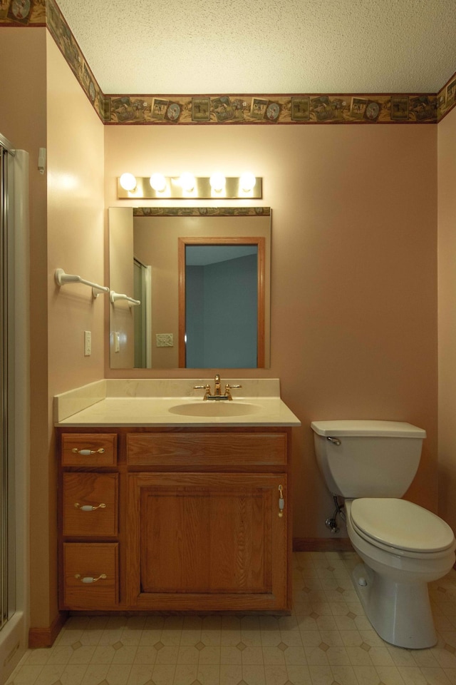 bathroom with vanity, toilet, a shower with shower door, and a textured ceiling