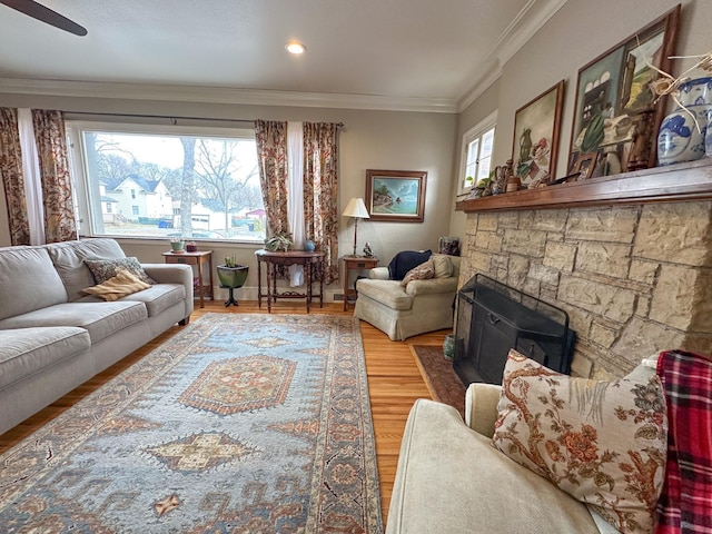 living room with hardwood / wood-style floors, a wood stove, ceiling fan, and crown molding