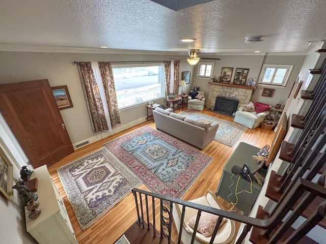 living room featuring a textured ceiling, ceiling fan, light hardwood / wood-style floors, and crown molding