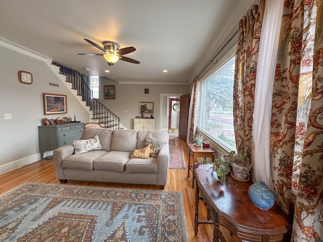 living area featuring light wood finished floors, ceiling fan, crown molding, stairs, and baseboards