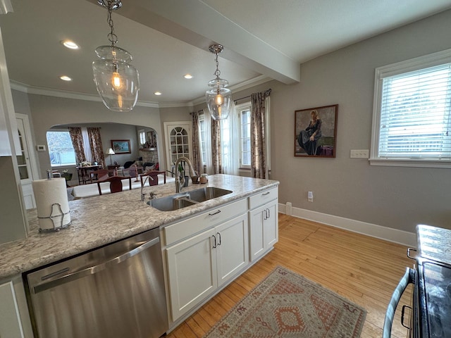 kitchen with stainless steel dishwasher, a sink, arched walkways, white cabinetry, and hanging light fixtures
