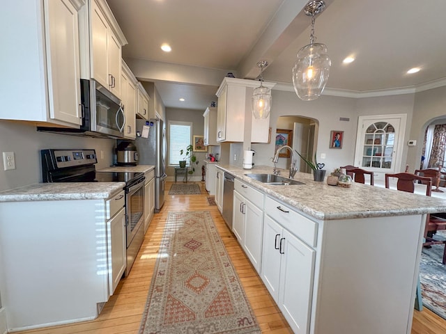 kitchen with appliances with stainless steel finishes, a sink, arched walkways, a peninsula, and light wood finished floors