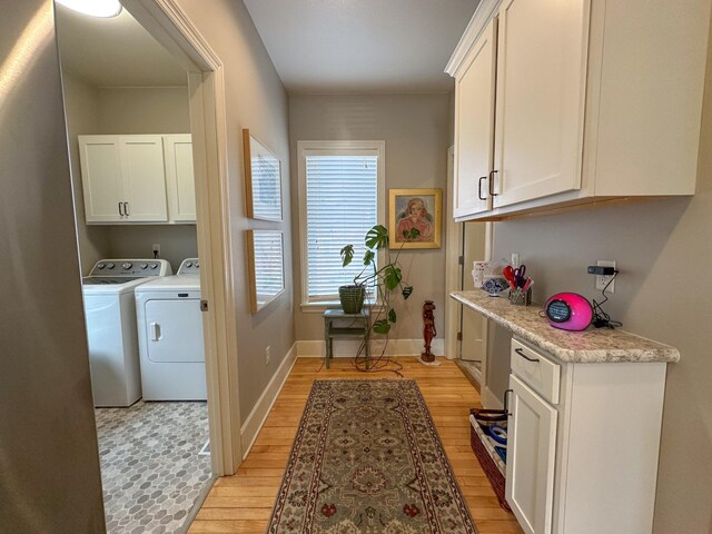 clothes washing area featuring washer and clothes dryer, cabinet space, light wood finished floors, and baseboards