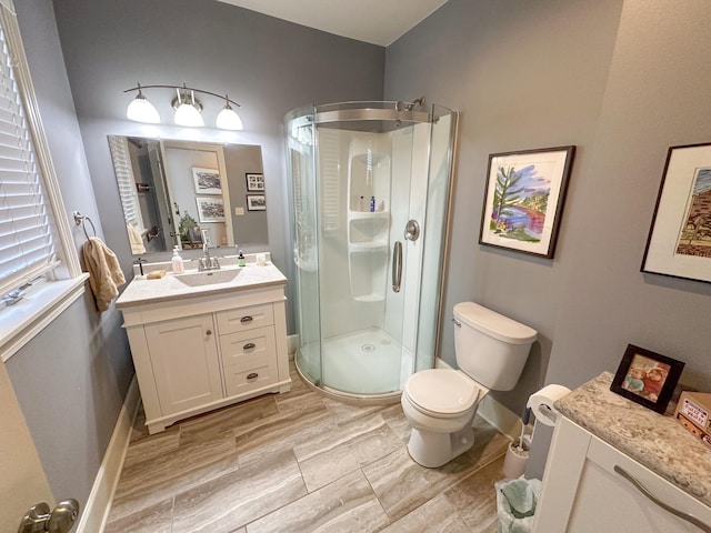 bathroom with a shower stall, vanity, toilet, and baseboards