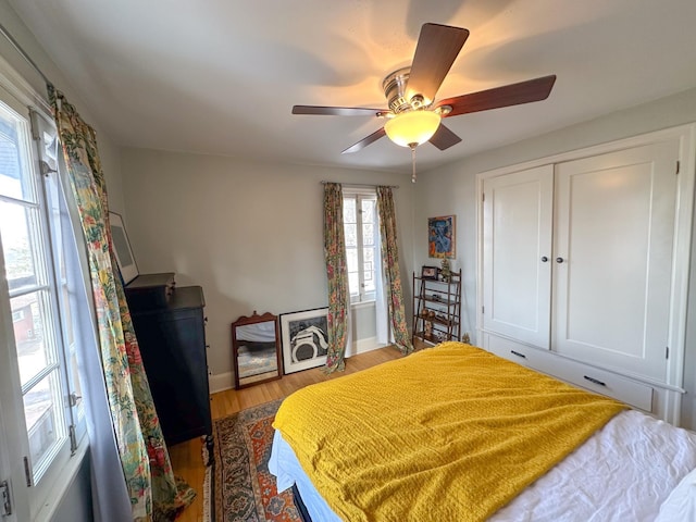 bedroom with wood finished floors, baseboards, and ceiling fan