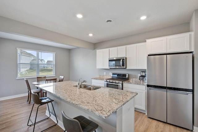 kitchen featuring sink, stainless steel appliances, light hardwood / wood-style flooring, an island with sink, and white cabinets