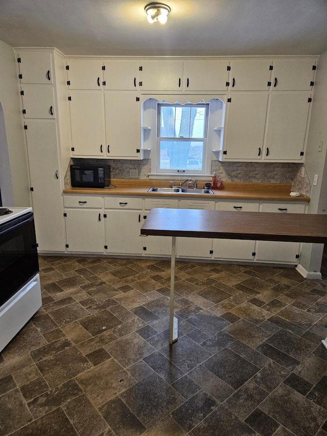 kitchen with stove, tasteful backsplash, white cabinetry, and sink