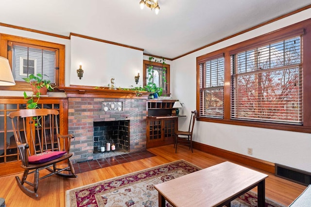 living room featuring hardwood / wood-style floors, crown molding, a fireplace, and a wealth of natural light