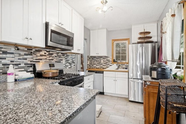 kitchen featuring decorative backsplash, white cabinetry, stainless steel appliances, and a textured ceiling