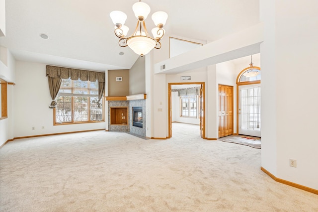 unfurnished living room with a chandelier, carpet, a tiled fireplace, and high vaulted ceiling