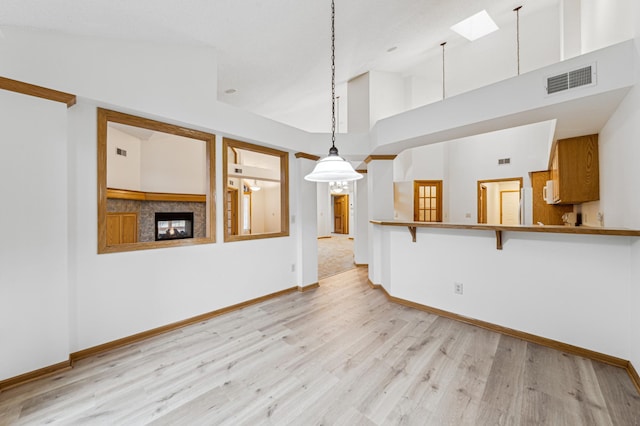 unfurnished living room featuring baseboards, light wood-style floors, visible vents, and high vaulted ceiling