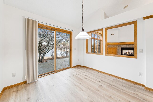 unfurnished dining area with wood finished floors, baseboards, and vaulted ceiling