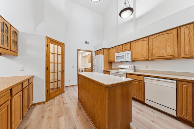 kitchen featuring a center island, glass insert cabinets, light wood-style floors, brown cabinetry, and white appliances