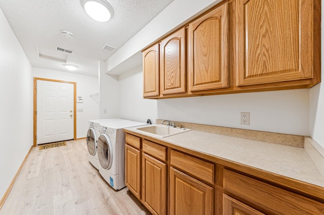 laundry room featuring cabinet space, visible vents, washer and dryer, and a sink