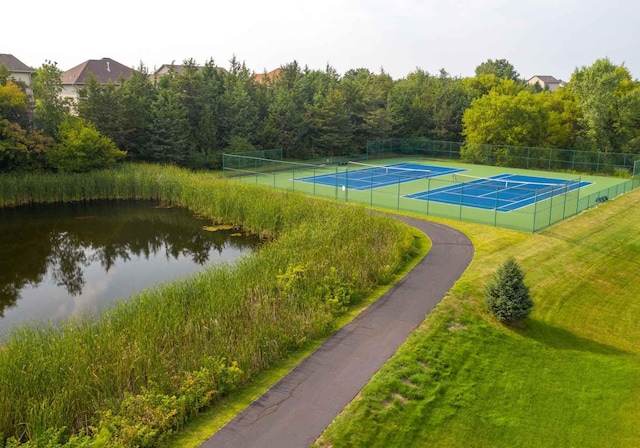 view of sport court featuring a water view, a lawn, and fence